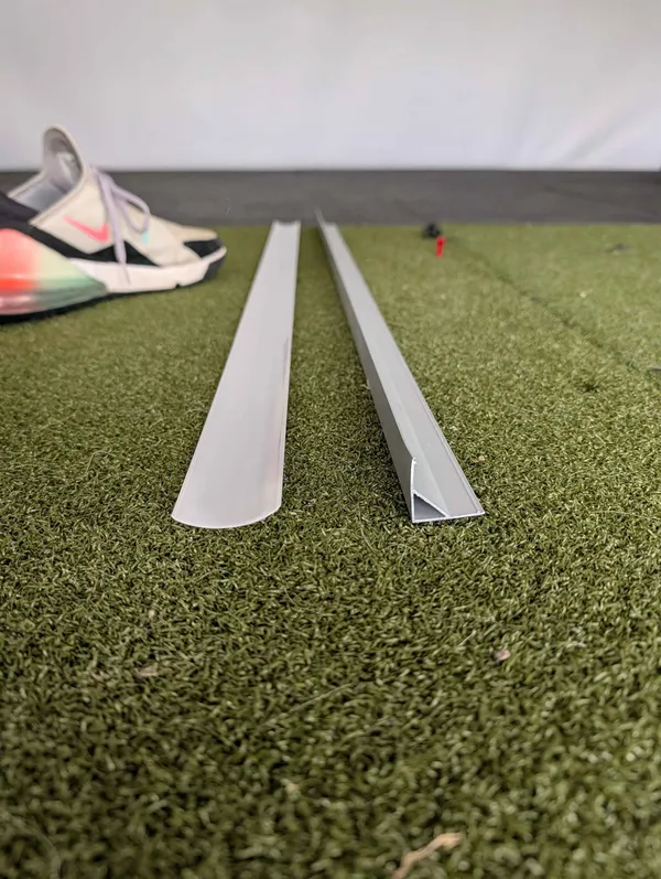Two aluminum LED diffuser channel profiles, one rounded and one 45-degree, laid on a putting mat.