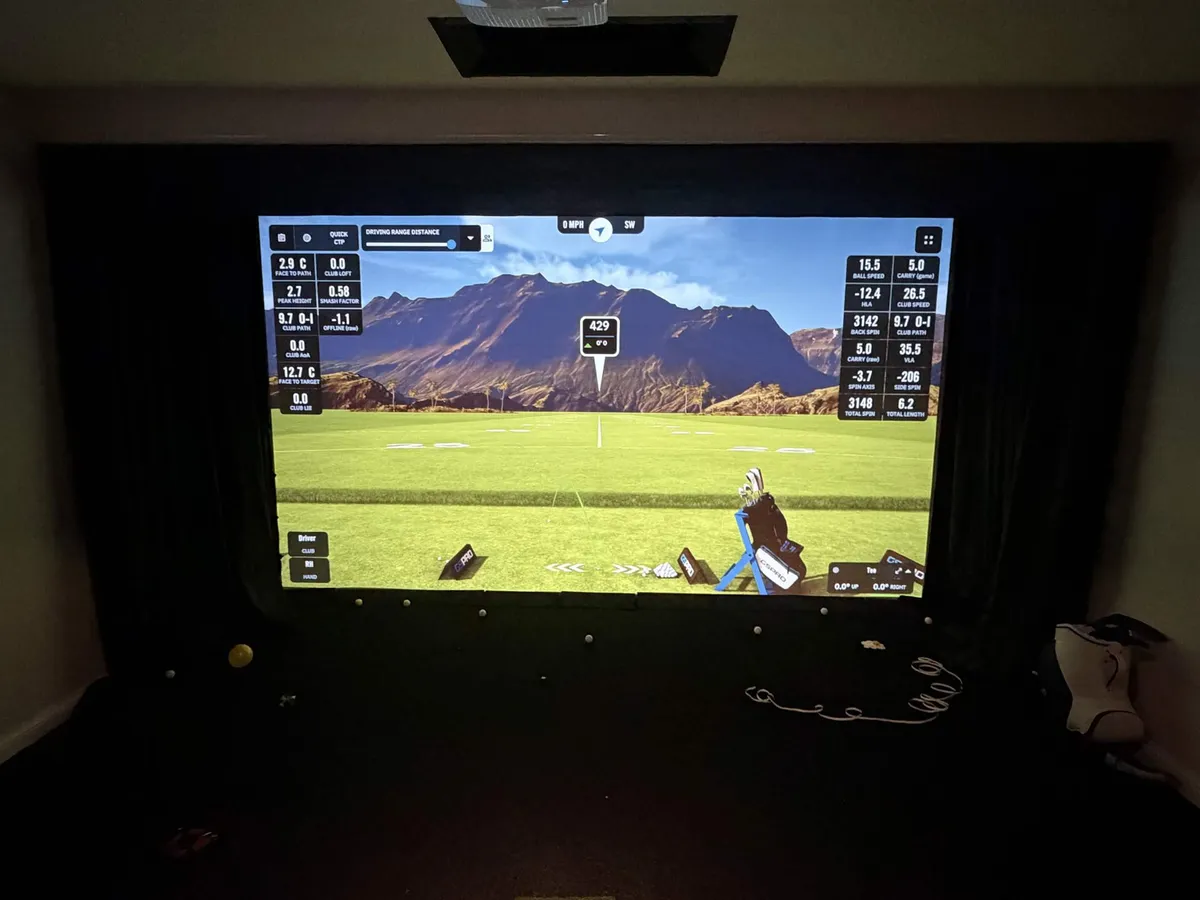 A darkened golf-sim room with the SimLight Golf strip sitting cleanly above the impact screen.