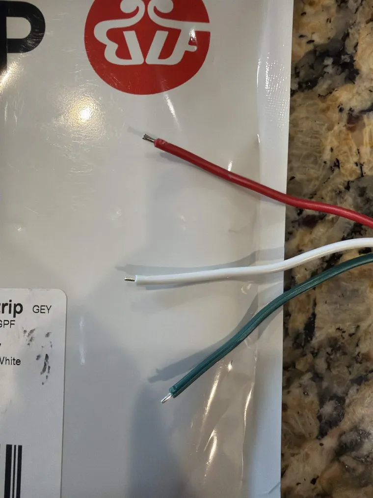 The LED strip's three bare leads: red for power, white for ground, and green for data, ready for a connector.